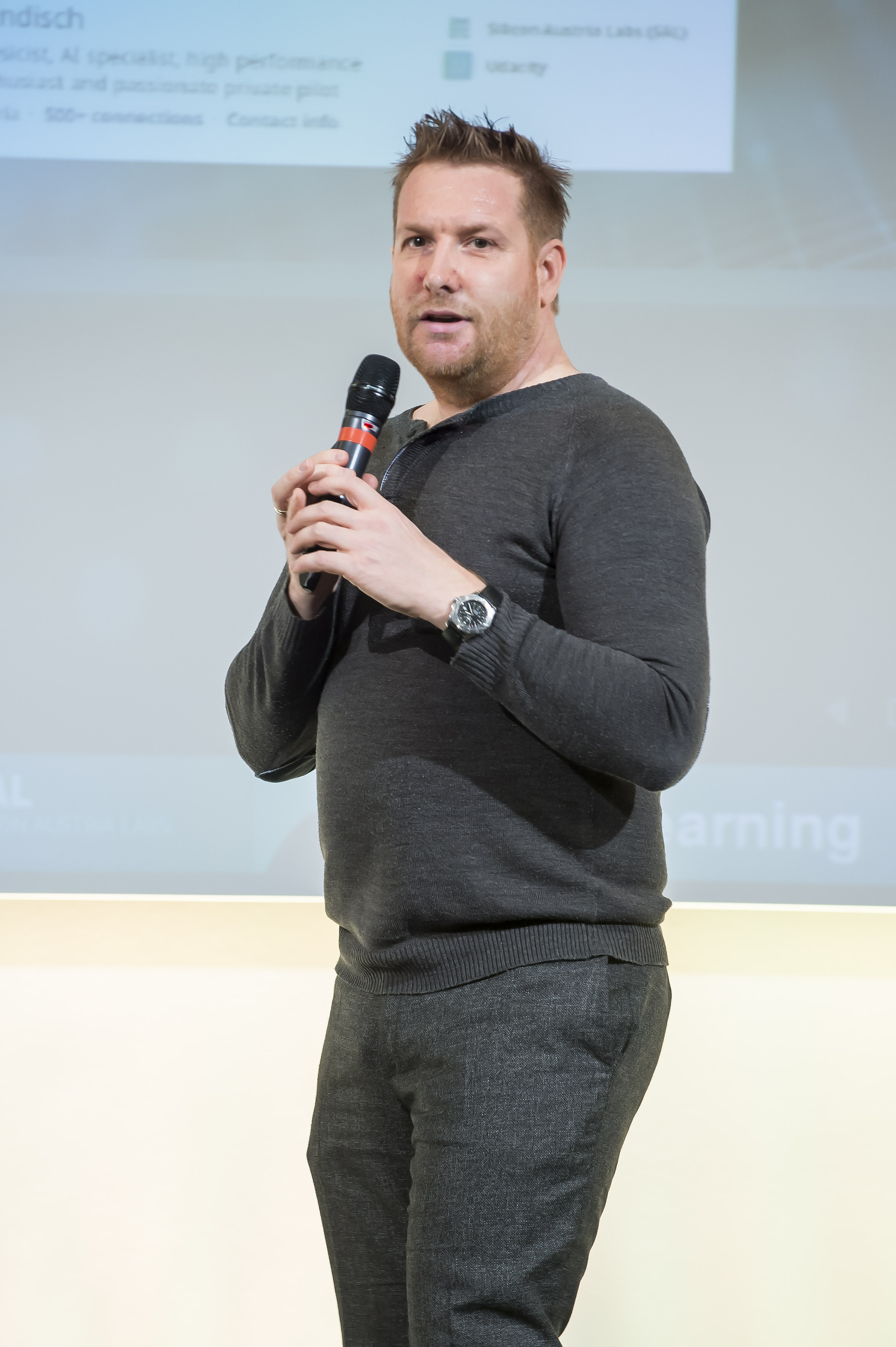Foto eines Vortragenden mit Mikrofon in der Hand