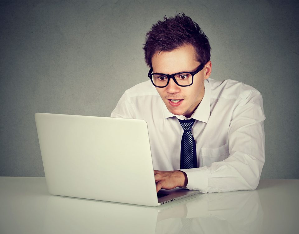 Foto eines jungen Mannes mit Anzug und Brille vor einem Laptop